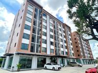 Un gran edificio con coches aparcados delante. en JIA HAUS Hotel Apartment, en Buriram