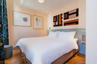 a bedroom with a large white bed and paintings on the wall at Hotel Mercier in Amsterdam