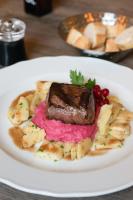 a plate of food with a piece of meat and bananas at Hotel Schloss Rattey in Schönbeck