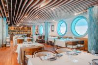 a restaurant with white tables and chairs and windows at Swissotel Buyuk Efes Izmir in Izmir