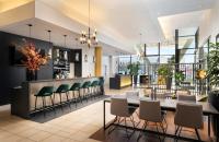 a lobby with a bar with green chairs at Leonardo Hotel Salzburg Airport in Salzburg