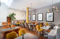 a dining room with tables and yellow chairs at Leonardo Hotel Salzburg Airport in Salzburg