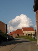aphalt street with buildings and a large cloud in the sky at The Lodge in Bilzen