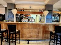 un bar en un restaurante con sillas negras en Auberge de l’Union, en Lens