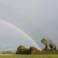 a rainbow in the sky over a field at Au pied de la colline in Alembon