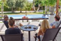 a group of people sitting around a table by a pool at Skiathos Holiday Resort in Skiathos