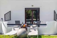 a patio with white chairs and a table and windows at Skiathos Holiday Resort in Skiathos