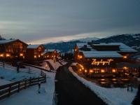 a town in the snow at night with lights at Bergdorf Hotel Zaglgut in Kaprun