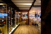 a restaurant with a wine cellar with white tables and chairs at Hotel Antonio in Zahara de los Atunes
