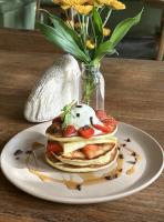 um prato de panquecas com morangos e um vaso de flores em Mule Malu Tropical Stay em Uluwatu