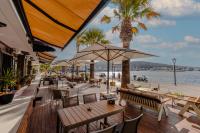 an outdoor restaurant with tables and chairs and palm trees at ERTAN OTEL in Cesme