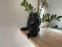a black vase sitting on a table with a plant at Magnifique logement avec terrasse &amp; climatisation in Aubervilliers