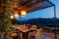 un tavolo e sedie in legno su un patio con vista sulle montagne. di Hôtel Case Latine a Lama
