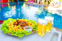 Ein Teller Essen und zwei Gläser Bier neben einem Pool in der Unterkunft Pousada das Galinhas in Porto De Galinhas