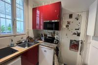 a kitchen with red cabinets and a white refrigerator at Charming apartment in the heart of Paris in Paris