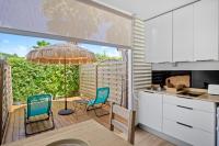 a kitchen with a patio with chairs and an umbrella at Studio Sunshine in Le Diamant