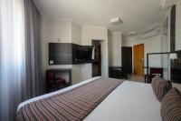 a hotel room with a bed and a television at Faro Hotel Taubaté in Taubaté