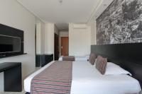a hotel room with a bed and a flat screen tv at Faro Hotel Taubaté in Taubaté
