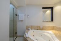 a bathroom with a tub and a glass shower at Faro Hotel Taubaté in Taubaté