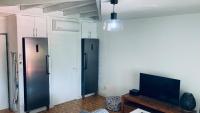 a living room with a black refrigerator and a tv at Duplex à 50m de la plage du Diamant avec parking in Le Diamant