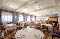 Un restaurante con mesas y sillas blancas y ventanas. en Hotel Robert, en La Pobla de Claramunt