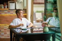 a man sitting at a table with a plate at Rendezvous Classic House in Chiang Mai