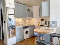 a small kitchen with white cabinets and a table at Appartement chic vue mer in Le Barcarès