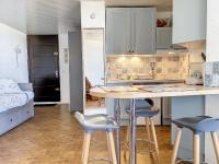 a kitchen with a table and stools in a room at Appartement chic vue mer in Le Barcarès
