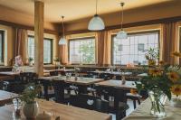 um restaurante com mesas e cadeiras de madeira e janelas em Landhotel Anna em Silandro