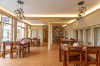 um restaurante com mesas e cadeiras de madeira e janelas em Sand Dunes Retreat em Leh