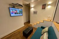 a living room with a couch and a tv on a wall at Lovely love nest near Paris in Clichy