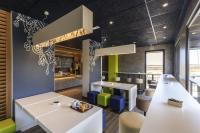 un restaurante con mesas blancas y sillas coloridas en Ibis Budget Valencia Alcasser, en Silla