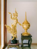 a gold statue of a woman on a table next to a vase at Rendezvous Classic House in Chiang Mai
