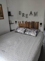 a bed in a bedroom with a dream sign on the wall at La Parenthèse Clissonnaise plein centre historique in Clisson