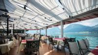 Un restaurante con mesas y sillas y vista al agua. en Romantik Residenz (Ferienwohnungen Hotel Im Weissen Rössl) - Dependance, en St. Wolfgang