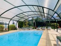 a swimming pool with a retractable canopy over it at La Blatière French Cottages in La Chapelle-Saint-Étienne