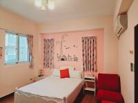 a bedroom with a bed and a red chair at Sunny Sun B&amp;B in Taitung City