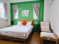 a green bedroom with a bed and a chair at Sunny Sun B&amp;B in Taitung City