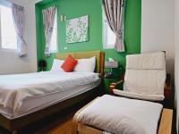 a bedroom with two beds and a green wall at Sunny Sun B&amp;B in Taitung City
