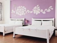 two beds with white flowers on a purple wall at Sunny Sun B&amp;B in Taitung City