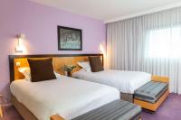 two beds in a hotel room with purple walls at Hotel Lille Euralille - Hilton Affiliate Hotel in Lille