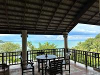 een tafel en stoelen op een balkon met uitzicht op de oceaan bij Kooncharaburi Resort - Koh Chang in Ko Chang
