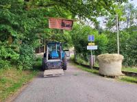 a tractor driving down a road with a sign at Gîte de la Ferme de la Comté in Le Thillot