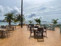 a wooden deck with tables and chairs and the ocean at Koh Mook Sivalai Beach Resort in Koh Mook