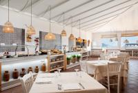 Un restaurante con mesas y sillas y una cocina. en VOI Colonna Village, en Golfo Aranci