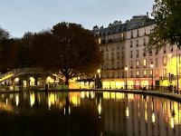 a river in front of a building at night at Rooms with fabulous view on Paris roofs in Paris