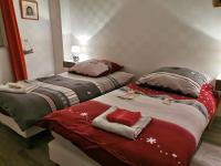 two beds in a room with red and gray blankets at La Maison Thébaïde in Mortagne