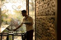 Un hombre sostiene una bandeja con un pastel. en Alila Solo, en Solo