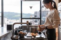 a woman standing in a kitchen preparing food at The Millennials Kyoto in Kyoto