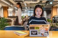a girl sitting at a table using a laptop computer at The Millennials Kyoto in Kyoto